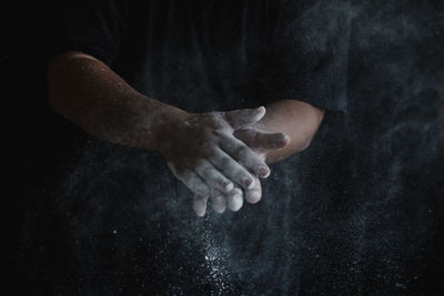 Low section of man sitting against black background