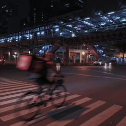 Blurred motion of people riding illuminated on road in city at night