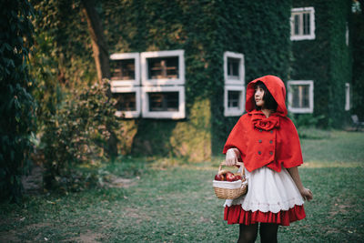 Full length of woman standing by red basket