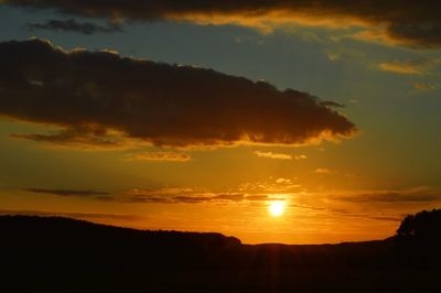 Scenic view of silhouette landscape against dramatic sky during sunset