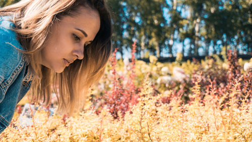 Close-up of woman looking at plants growing on field