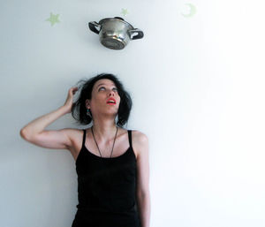 Woman looking up at cooking pan against wall at home