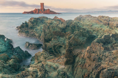 Scenic view of sea and island against sky during sunset