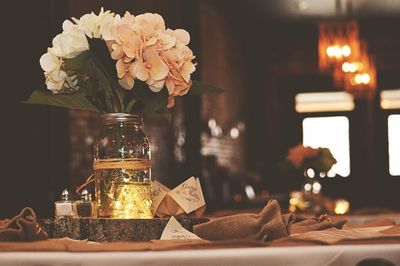 White flowers in jar on tree stump in wedding