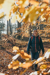 Woman with backpack wandering in a forest on autumn sunny day