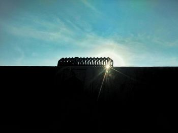 Low angle view of silhouette building against sky during sunny day