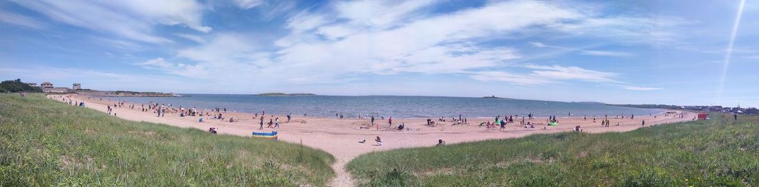 Panoramic view of people on beach against sky