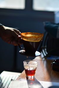 Close-up of hand holding tea cup on table
