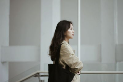 Side view of young woman standing indoors