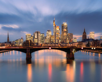 Illuminated bridge over river against sky at sunset