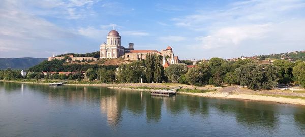 Buildings by river against sky