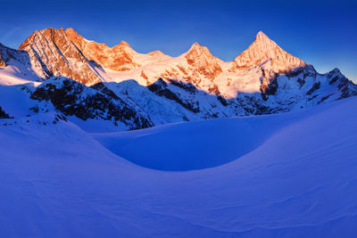 Scenic view of snowcapped mountains against blue sky