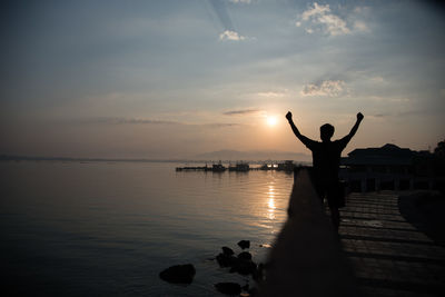 Silhouette of man by sea against sky during sunset