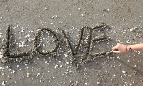 Cropped hand making love text on sand at beach