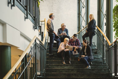 Multi-ethnic business people discussing on staircase of creative office