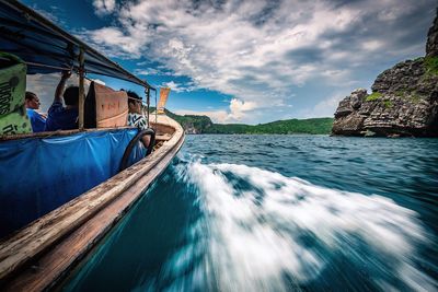 People in boat sailing on sea against sky