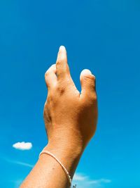 Close-up of hand against blue sky