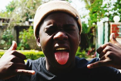 Close-up of young man sticking out tongue against plants