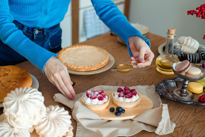 Beautiful girl in blue sprinkle the cake with powdered sugar. the white kitchen is in the background