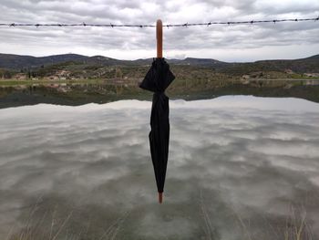 Reflection of wooden post in lake against sky
