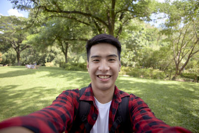 Portrait of smiling young man standing against trees