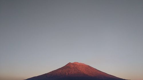 Low angle view of volcanic mountain against clear sky