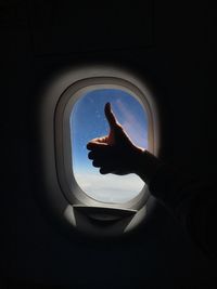 Close-up of silhouette hand on window