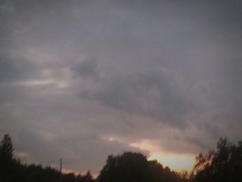 Silhouette of trees against cloudy sky