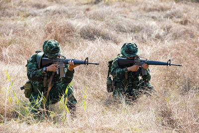 Army soldiers shooting with rifle on field