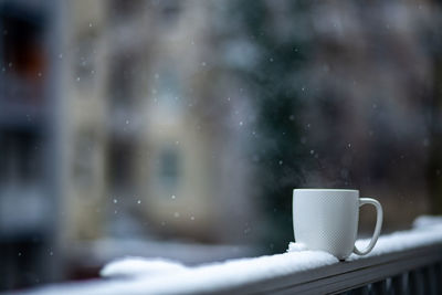 Close-up of coffee cup on window during winter