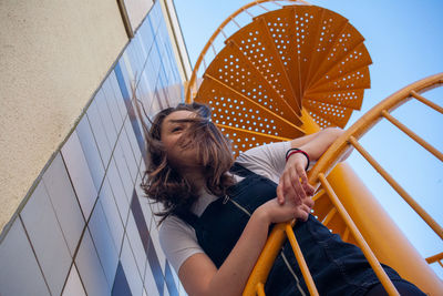 Low angle view of woman standing on steps against sky