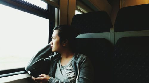 Thoughtful woman looking away while traveling in train