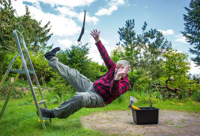 Senior man falling from ladder in garden