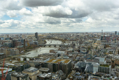 Aerial view of cityscape against cloudy sky