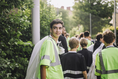 Teenage boy wearing reflective clothing holding garbage bag