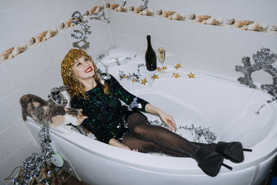 New years party birthday celebration. happy young woman in evening dress sitting in the bathtub