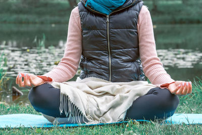 Midsection of man sitting by lake