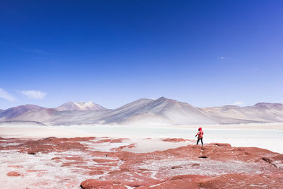 Man walking on mountain against blue sky