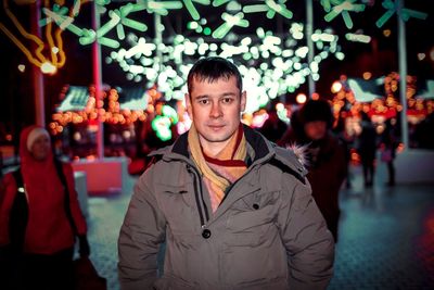 Portrait of man in illuminated christmas tree in winter