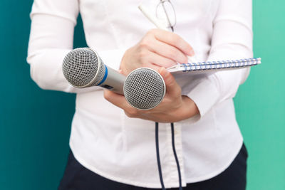 Midsection of female journalist holding microphone