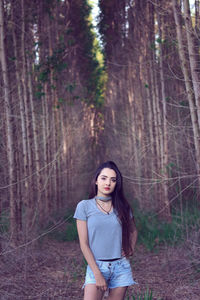 Portrait of young woman standing at forest