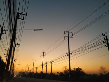 Low angle view of silhouette electricity pylon against sky during sunset