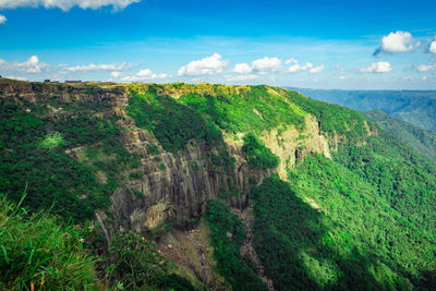 Mountain range covered with green forests and bright blue sky at afternoon from flat angle