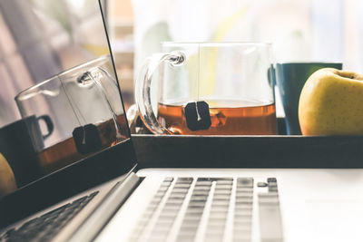 Close-up of laptop on table with coffee and apple