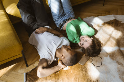 High angle view of smiling man and woman lying on floor at home