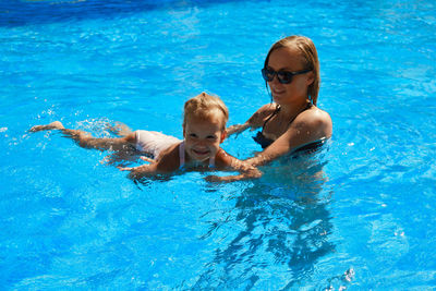 High angle view of mother and daughter swimming in pool