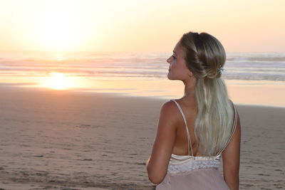 Woman standing at beach during sunset