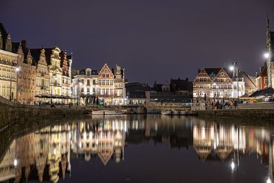 Reflection of illuminated buildings in lake against sky at night