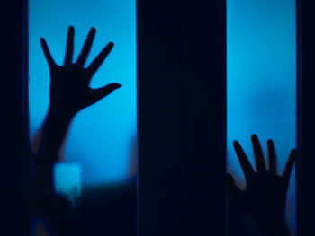Close-up of silhouette hand on glass window