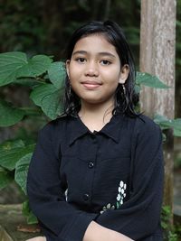 Portrait of young woman standing against plants
